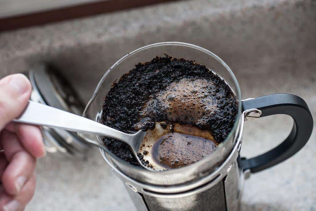 A close-up view of coarsely ground coffee beans in a French press, showcasing the ideal grind size for this brewing method