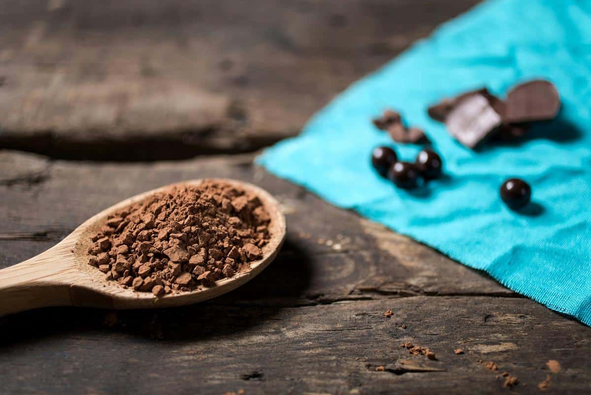 A bowl of rich, dark natural cocoa powder on a wooden surface